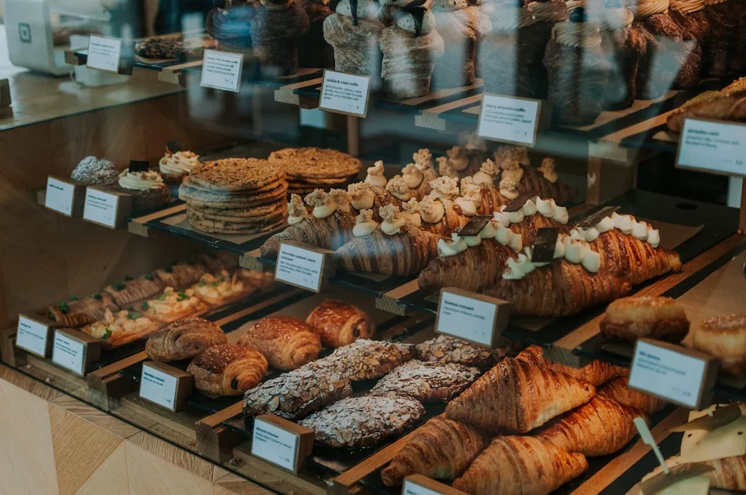 Assorted pastries and baked goods displayed on wooden trays behind a glass case in a charming Alaró bakery, known for its gourmet coffee and inviting pastry shop atmosphere.