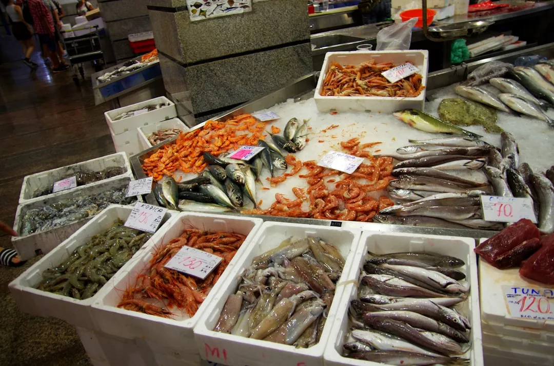 Fresh seafood displayed on ice at a Cala d’Or market, featuring fish, shrimp, and squid in white containers with price tags—ideal for gourmet dining enthusiasts.