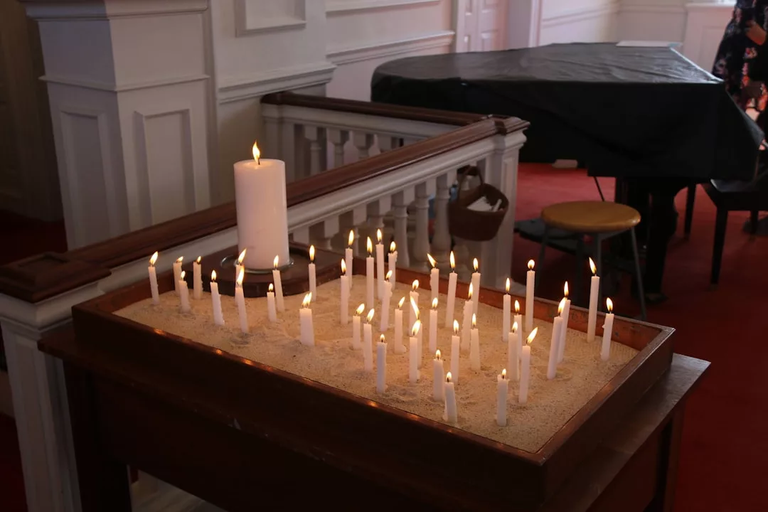 White candles burn in a tray of sand inside a church, with one large candle at the back—capturing the serene atmosphere found in Palma’s Gothic Quarter, where hidden speakeasy restaurants wait to be discovered.